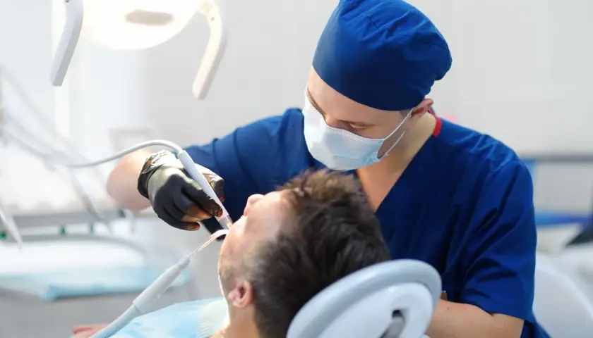 Dentysta w masce i rękawiczkach wykonuje zabieg. Sen o dentystach może oznaczać troskę o zdrowie lub potrzebę zmian.