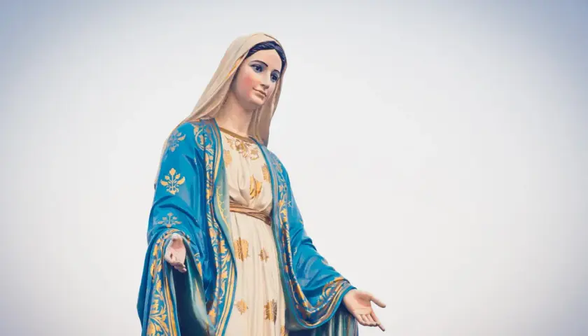 Posąg Matki Boskiej w niebieskim płaszczu ze złotymi zdobieniami, jakby witała rycerzy Maryi.