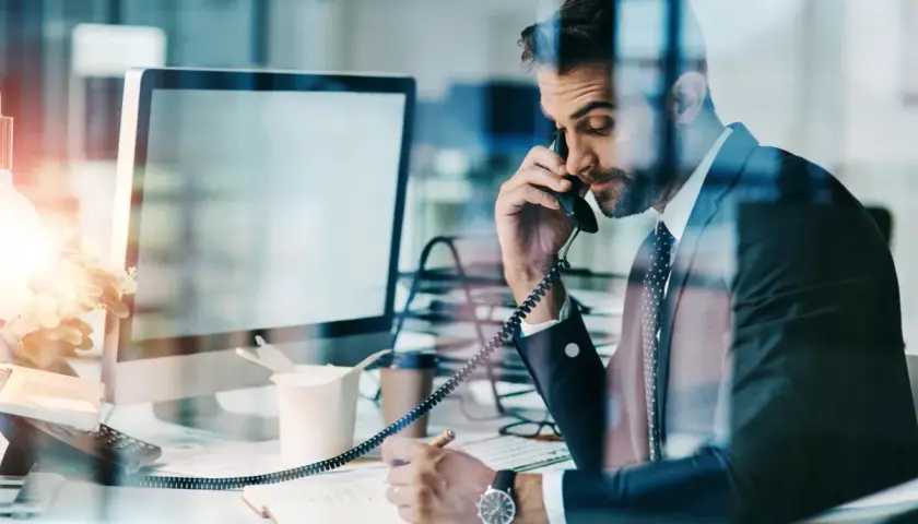 Biznesmen w garniturze rozmawia przez telefon, notując ważne informacje. Czasem czuje, że to **siła wyższa** kieruje jego karierą.