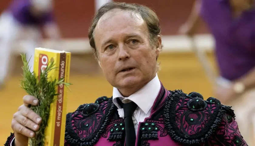 José Vázquez, torero con traje de luces, sostiene un ramo de romero y una caja amarilla.