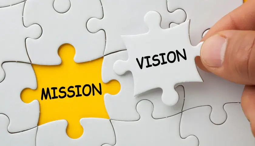Dłoń dopasowuje element układanki z napisem "VISION" do pola z napisem "MISSION", symbolizując wizję firmy.