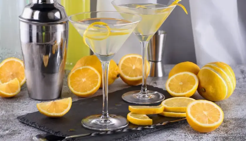 Dwa kieliszki z martini, cytryny i shaker. Idealne na orzeźwiający drink.