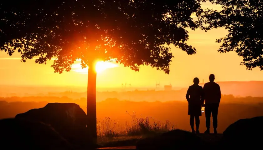 Ein Paar steht im Sonnenuntergang. Sie hat einen neuen Partner nach dem Tod ihres Ehemannes gefunden und blickt hoffnungsvoll in die Zukunft.