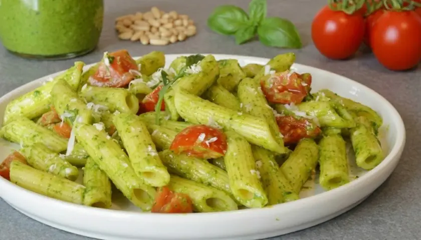 Penne al pesto di rucola con pomodorini freschi e pinoli tostati. Un piatto colorato e saporito.