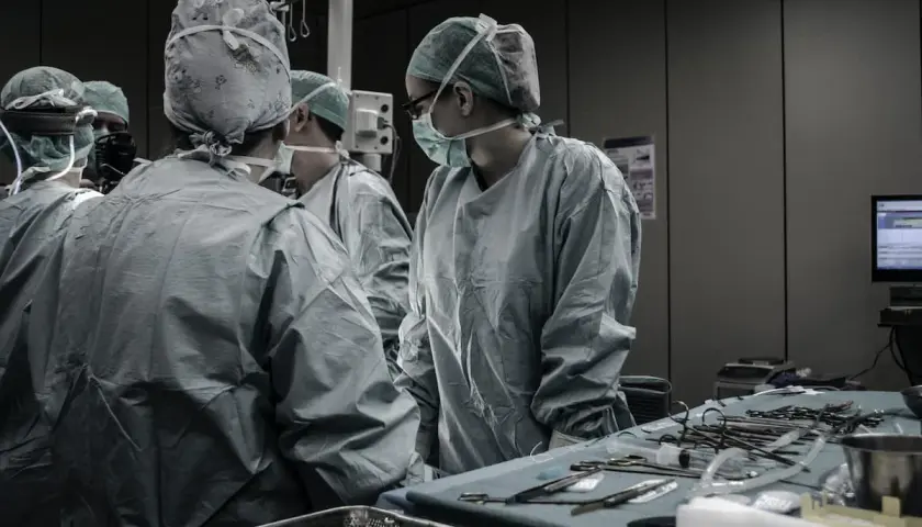 Chirurghi in sala operatoria discutono. Quanto guadagna un medico legale al mese? La risposta è complessa, ma il loro lavoro è fondamentale.