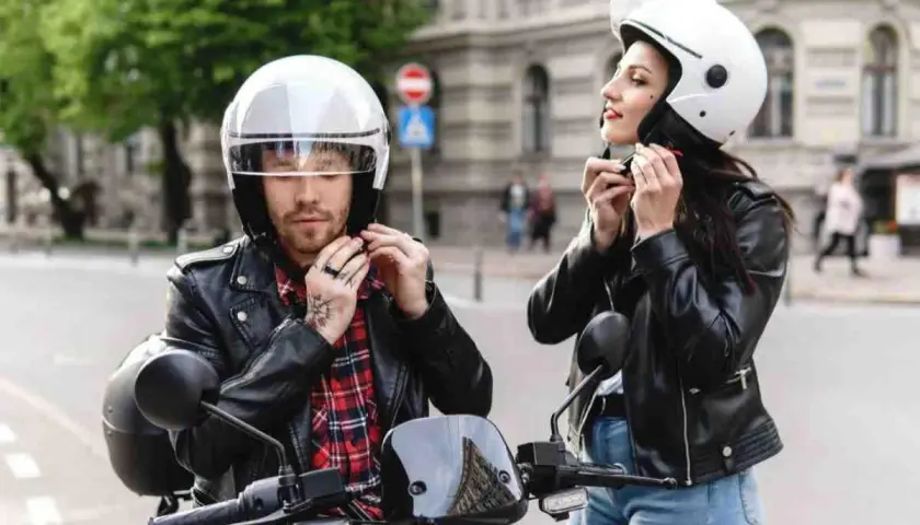 Coppia in moto, lui sistema il suo casco nuovo che fa male, lei il suo.