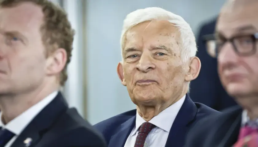 Jerzy Buzek, w otoczeniu innych mężczyzn, z uwagą słucha przemówienia.