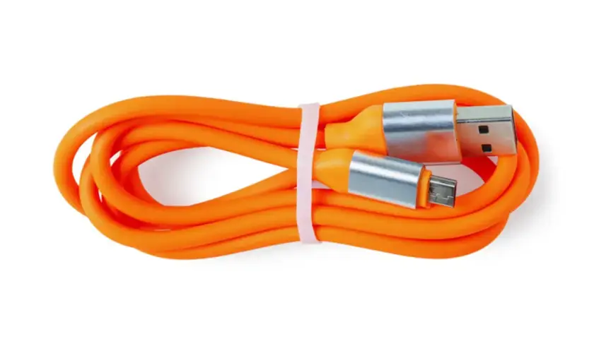 Pomarańczowy kabel USB z wtyczkami USB-A i micro USB, zwinięty i związany różową gumką.