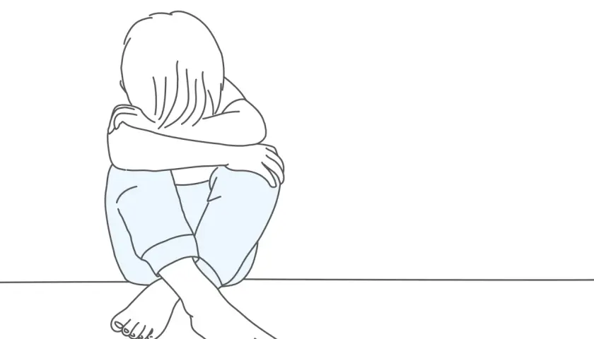 Smutne dziecko skulone na podłodze. Psychologia oceniająca innych często prowadzi do poczucia izolacji i smutku.