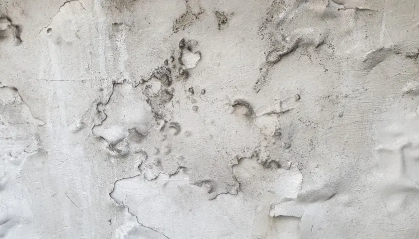 Abblätternder Putz auf Mauerwerk, gezeichnet von Salpeterablagerungen.