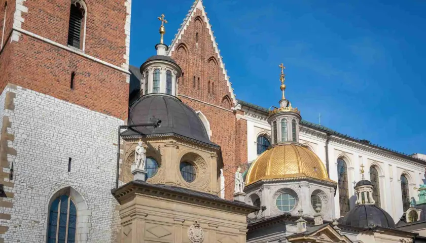 Katedra Wawelska z bliska: ceglana wieża, złota i czarne kopuły, detale architektoniczne.