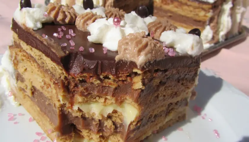 Tarta de galletas de la abuela de toda la vida, con capas de crema y chocolate, decorada con nata y granillo rosa.