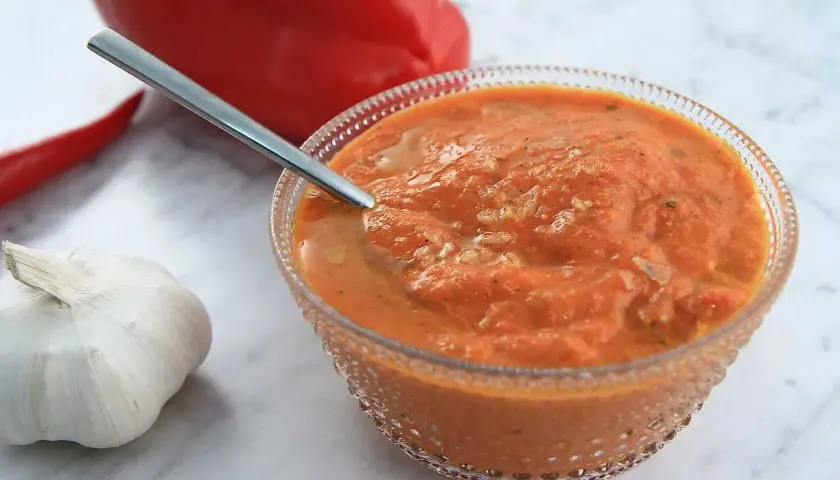 En skål med ajvar, en röd paprika och vitlök. Perfekt för ditt ajvar recept!