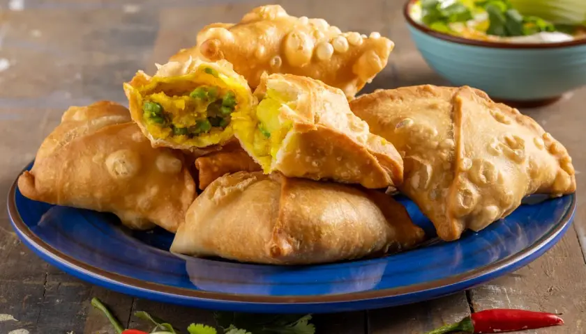 Samosa al forno dorati e croccanti, ripieni di verdure speziate. Un contorno piccante con peperoncino e coriandolo.