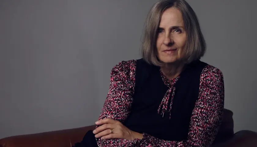 Susanna Alakoski, en svensk författare, sitter på en brun soffa med armarna korslagda.