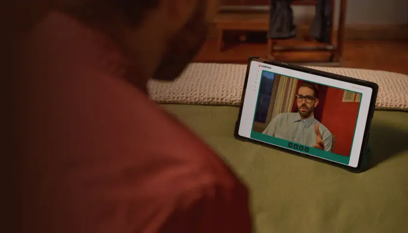 Uomo guarda un video su tablet. Sullo schermo, un uomo con occhiali parla, forse dando uno bravo recensioni.
