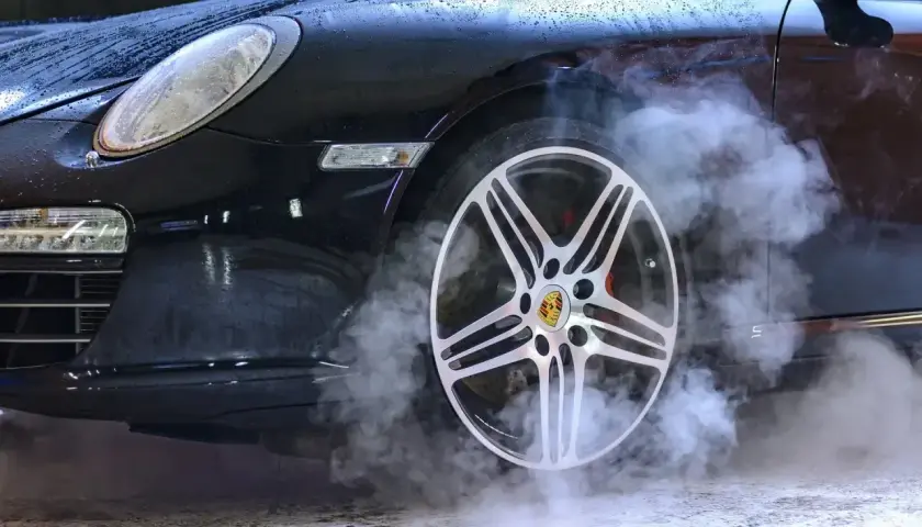 Czarny Porsche z dymem unoszącym się z koła. Zastanawiasz się, ozonowanie samochodu ile czasu zajmuje?