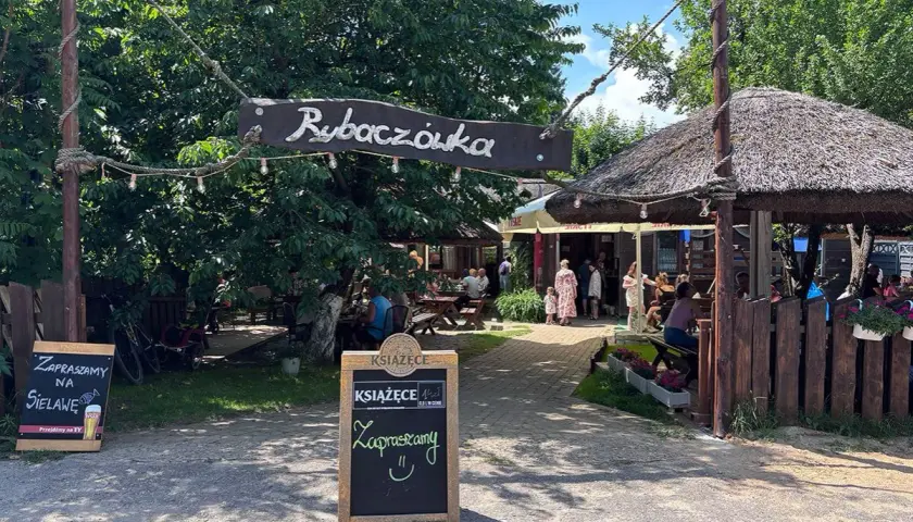 Rybaczówka zaprasza na sielawę. Letni ogródek z drewnianymi stołami i strzechą zachęca do odpoczynku.