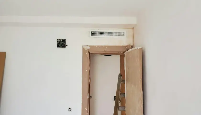 Instalación de rejilla para montaje de aire acondicionado sobre puerta en obra.