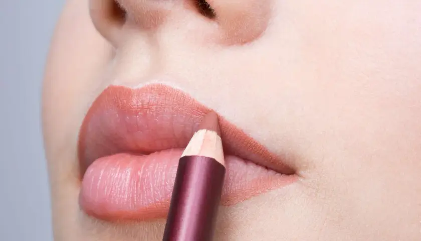 Close-up of lips with a lip liner pencil being applied.