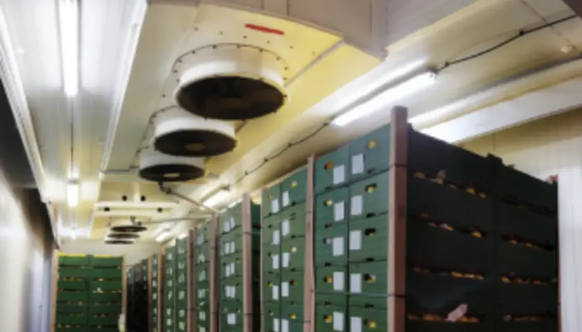 Almacén con cajas apiladas y ventiladores en el techo para el sistema de refrigerante CO2.