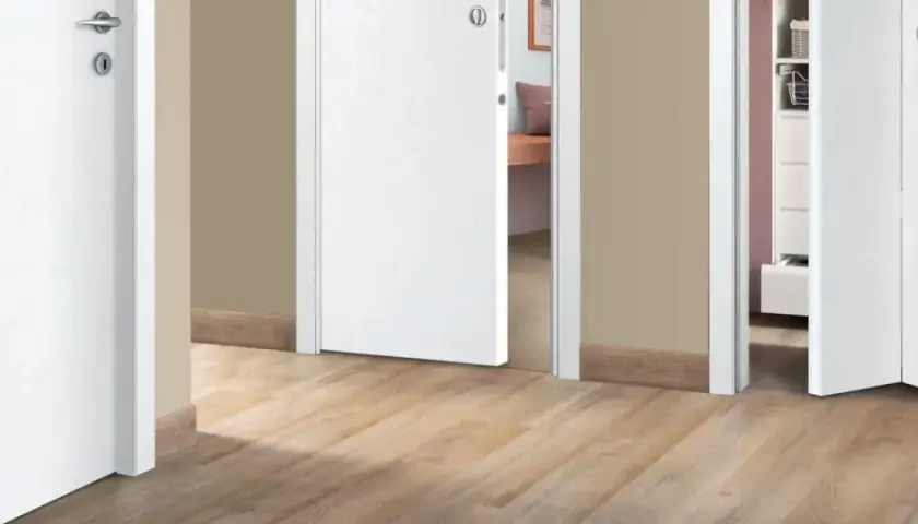 Corridoio con pavimento chiaro e porte interne bianche che creano un ambiente luminoso e moderno.