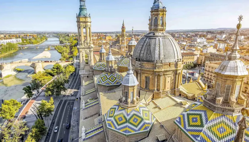 Vistas aéreas de la Basílica del Pilar en Zaragoza, con el río Ebro y puentes. Imagina un viaje en tren Sevilla Zaragoza para ver esta maravilla.
