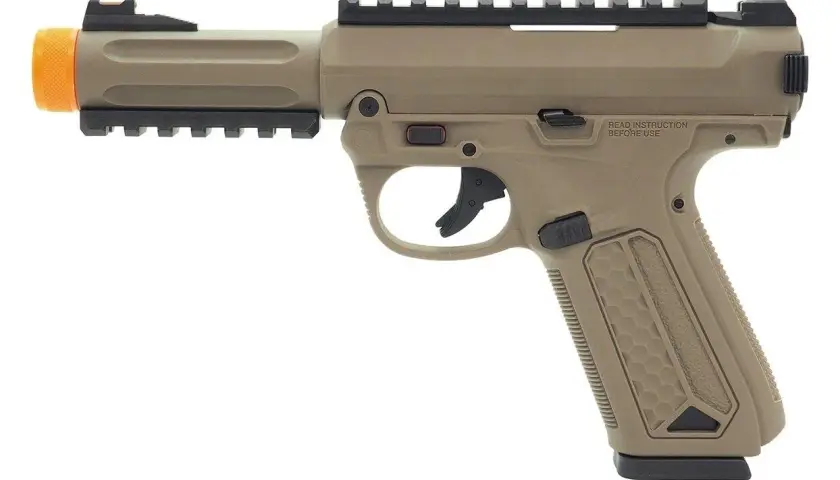 Beżowy pistolet ASG sprężynowy z pomarańczową lufą i szynami montażowymi.