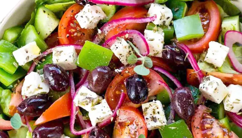 Insalata greca colorata con cubetti di feta, pomodori, olive, cetrioli e cipolla rossa. Il sapore fresco e mediterraneo è invitante.