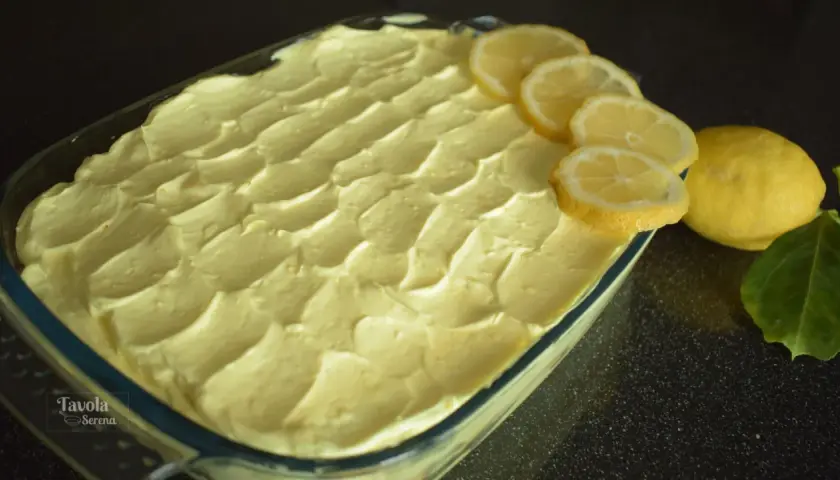 Tiramisù al limone pronto per essere gustato, decorato con fette di limone fresco e limoni interi.