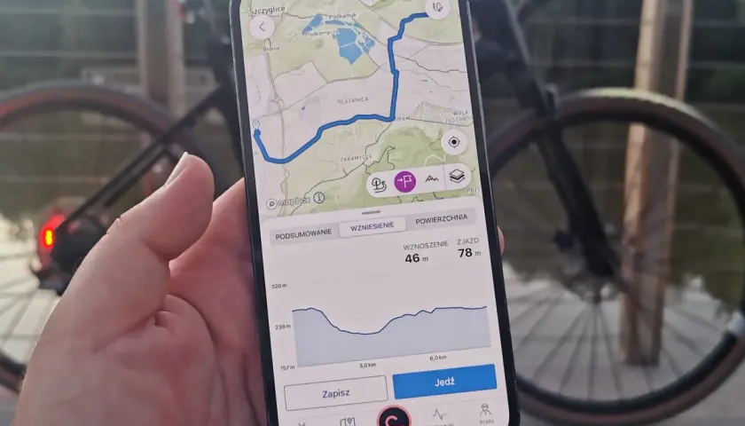 Mapa z trasą rowerową na telefonie, pokazująca drogi leśne dopuszczone do ruchu. Widok profilu wysokości i przycisk "Jedź".