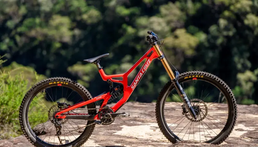 A bright red Santa Cruz V10 downhill bike sits on rocks, ready for its next review.