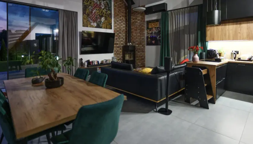 Nowoczesny salon z jadalnią i aneksem kuchennym. Stylowe wykończenie domu, gdzie koszty idą w parze z designem.