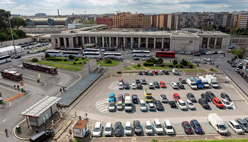 Ampio parcheggio di autobus e auto vicino alla stazione metro di Roma. Molti mezzi di trasporto pubblico e privato in un'area trafficata.