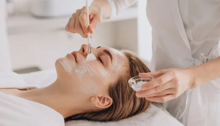 Delikatny peeling enzymatyczny w ciąży. Kosmetolog nakłada maskę na twarz kobiety, dbając o jej komfort i bezpieczeństwo.
