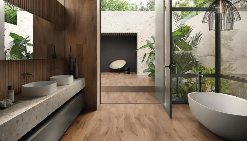 Bagno moderno con vasca freestanding, doppio lavabo e piante rigogliose. Un esempio di raffinate ristrutturazioni interne che uniscono natura e design.