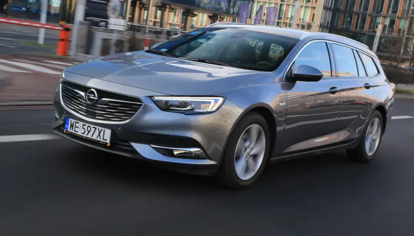Szary Opel Insignia 2.0 CDTI w wersji kombi jedzie po miejskiej drodze.