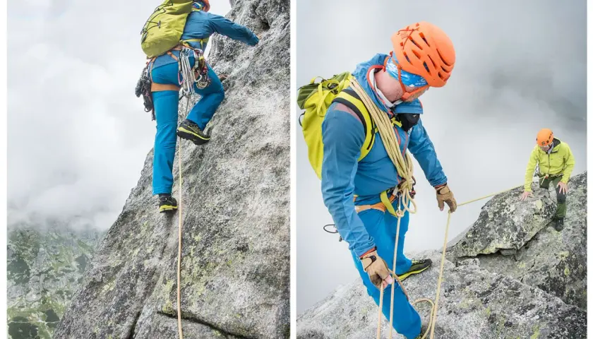 Dwóch alpinistów wspina się na mnicha w Tatrach. Jeden z nich, w niebieskiej kurtce, pokonuje skalną ścianę, drugi, w zielonej kurtce, asekuruje go.