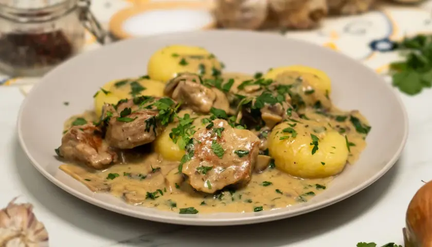 Polędwiczki w sosie pieczarkowym z ziemniakami, posypane natką pietruszki. Pyszne danie obiadowe.