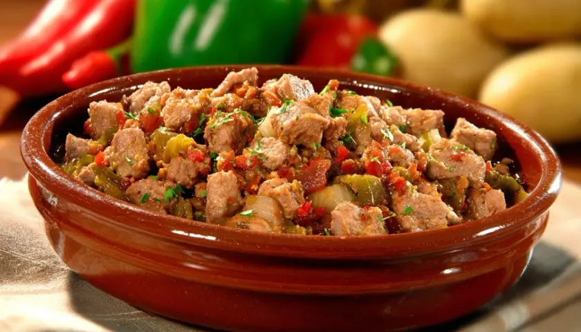 Un plat d'axoa de veau mijoté avec des poivrons et des oignons, garni de persil frais, dans un bol en terre cuite.