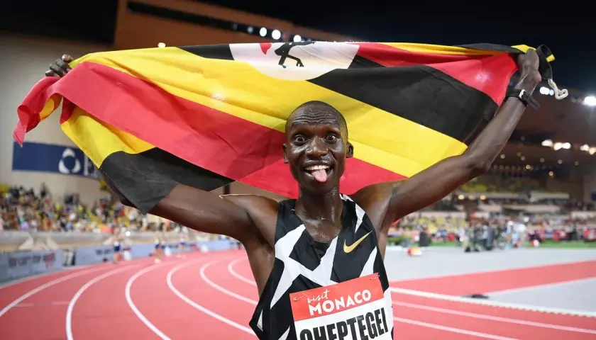 Joshua Cheptegei z flagą Ugandy świętuje swój rekord świata na 5km.