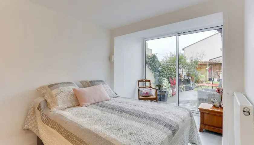 Chambre lumineuse avec vue sur jardin, résultat d'une belle idée : transformer un garage en habitation. Lit douillet, mobilier cosy.
