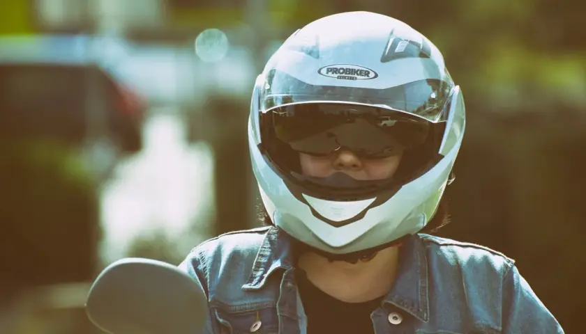 Motociclista con casco jet, che offre una visione chiara, a differenza di un casco demi jet. Indossa giacca di jeans.