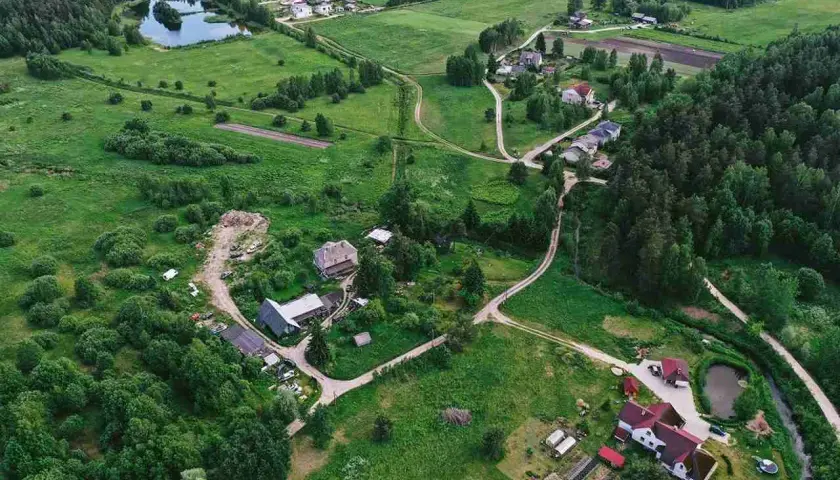 Wieś z domami i drogami, gdzie służebność gruntowa może dotyczyć dostępu do jeziora lub lasu.