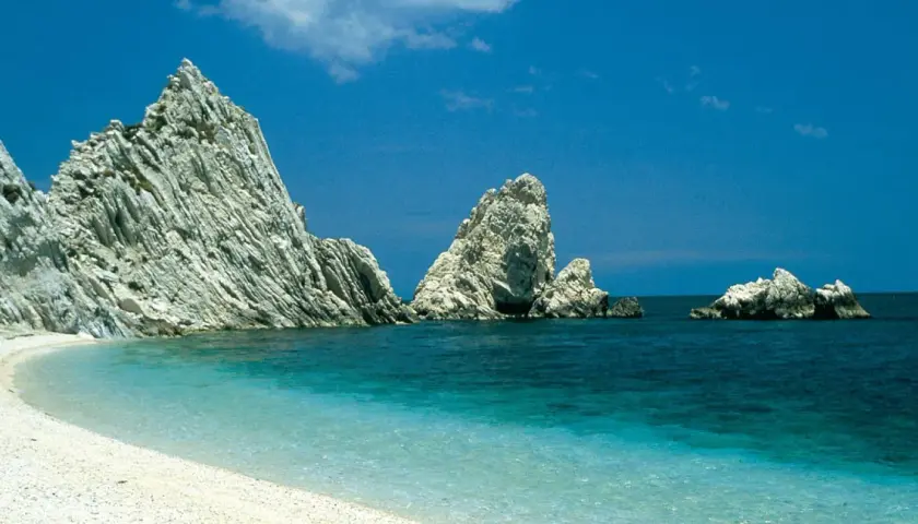 Spiaggia bianca e mare cristallino con faraglioni imponenti, un sogno per le vacanze Marche mare.