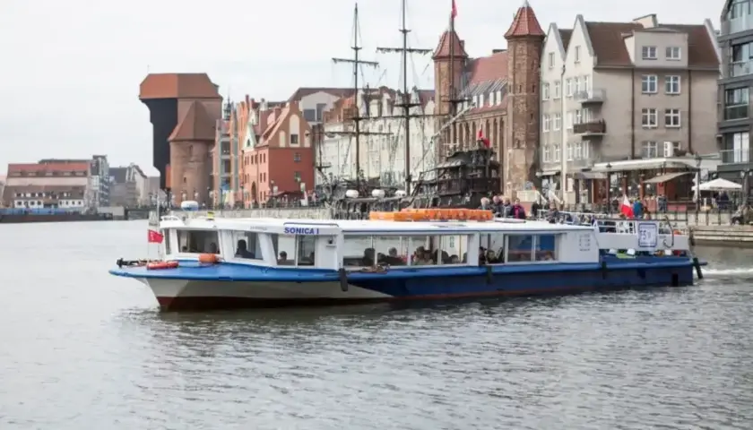 Pasażerski tramwaj wodny "Sonica I" płynie Motławą na tle zabytkowej zabudowy Gdańska.