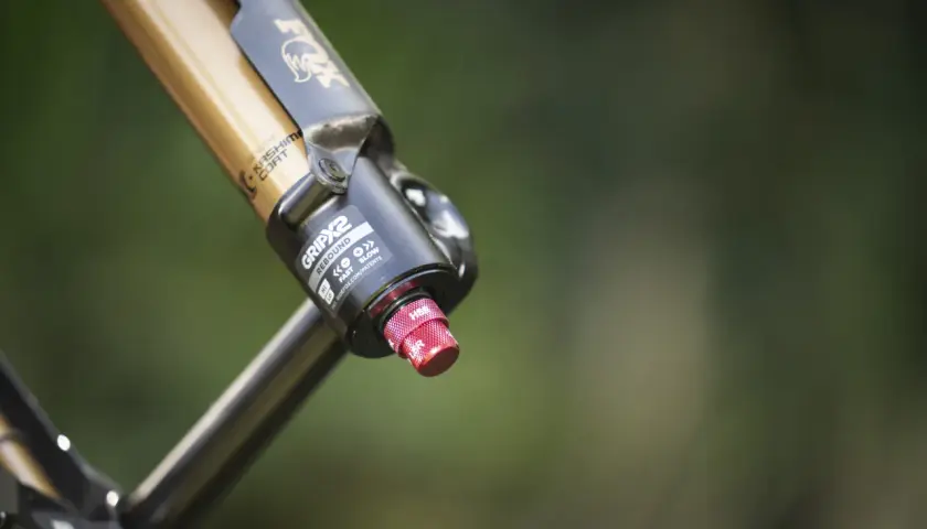 Close-up of a gold and black Fox 36 FIT4 fork with Kashima Coat, featuring the GRIP2 damper and a red adjustment knob.