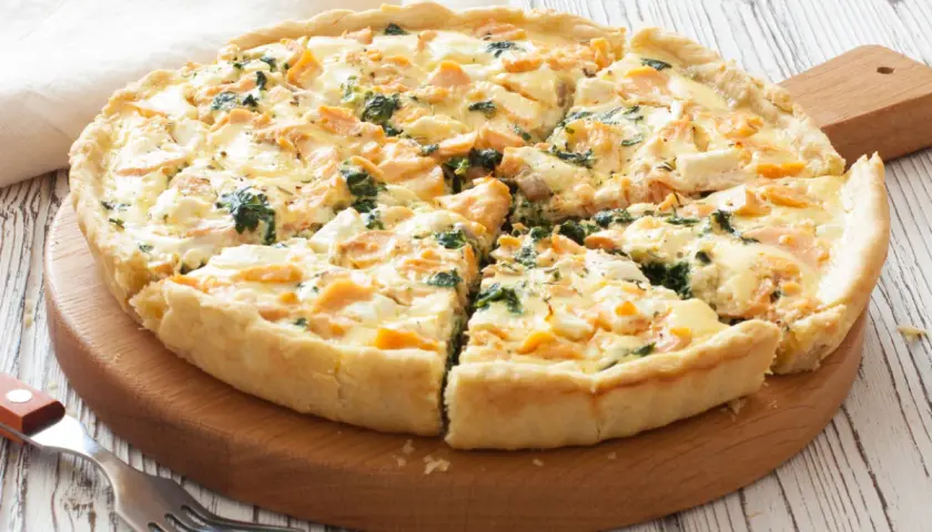 Pyszna tarta z łososiem, szpinakiem i serem feta, pokrojona na kawałki, gotowa do podania.