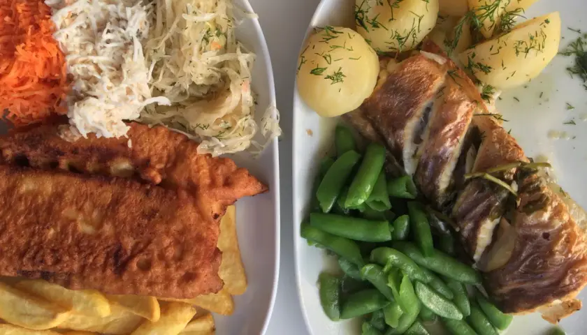 Dwa talerze pysznego jedzenia, idealne pytanie: gdzie zjeść w Gdyni? Ryba z ziemniakami i fasolką, a obok panierowany filet z frytkami i surówkami.