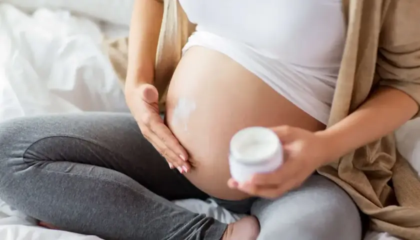 Gravid kvinna smörjer magen med kräm. Vissa krämer innehåller salicylsyra, vilket kan vara bra att veta för dig som är gravid.